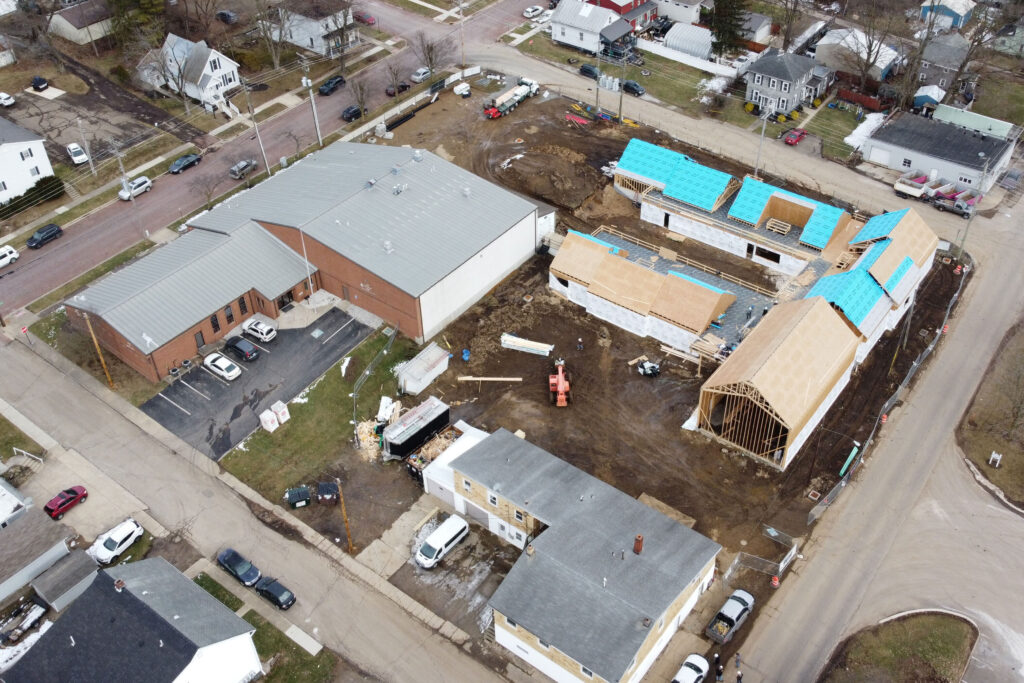 Aerial view of The Salvation Army Learning Lighthouse under construction in January 2025. The child care center features multiple connected buildings with partially completed roofs. To the left is the existing Mount Vernon Corps Community Center, and at the bottom is a storage and laundry building. Construction materials and vehicles are scattered across the site.
